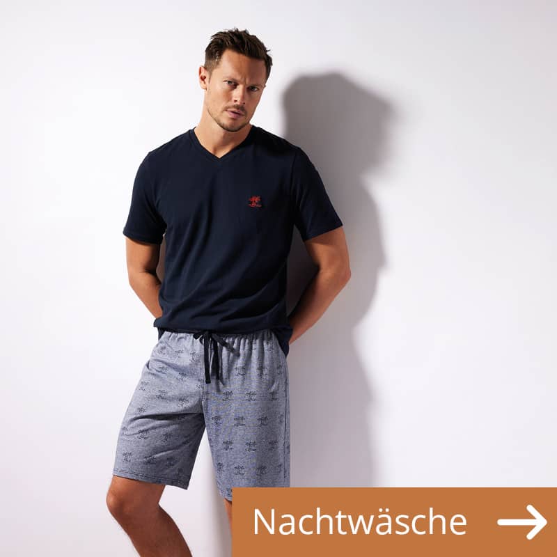 Ein Mann trägt eine Nachtwäsche Kombination aus kurzer Schlafhose und einem Schlaf-Shirt.