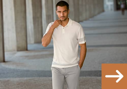Ein Mann trägt ein weißes Polo-Shirt und eine graue Chino-Hose.