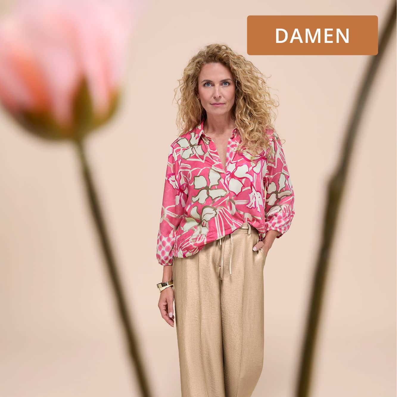 Frau mit Bluse mit floralem Print und einer leichten Stoffhose